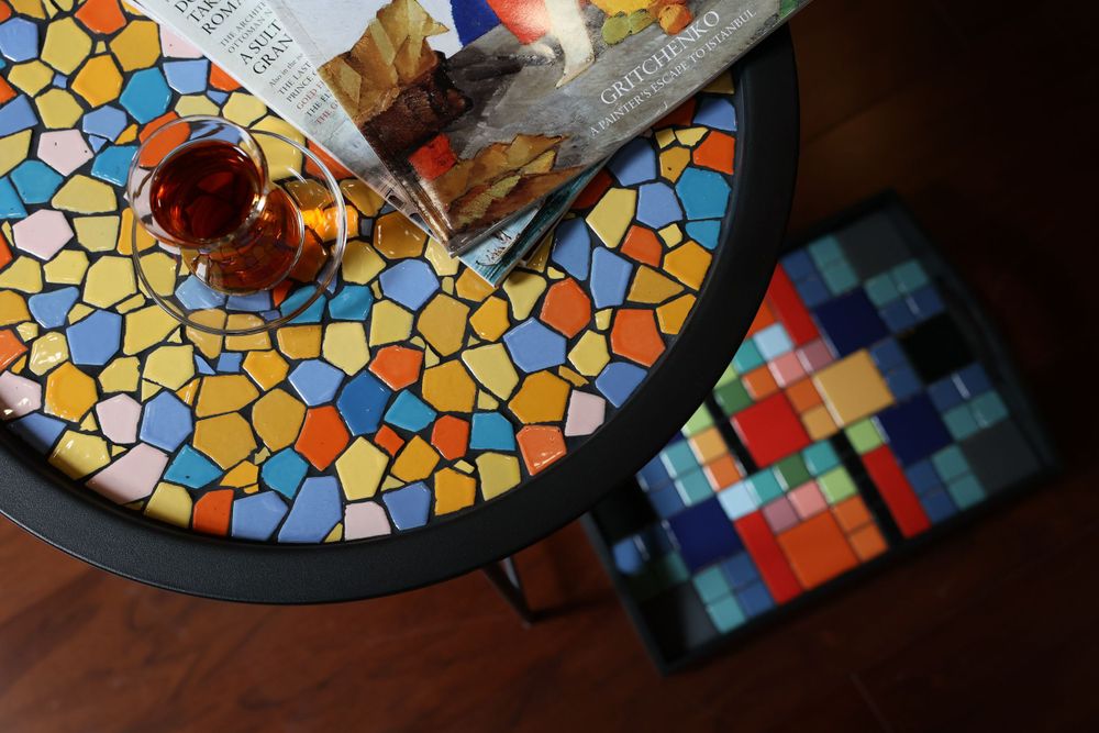 Close-up view of mosaic serving tray with geometric patterns in orange, blue and yellow colors.