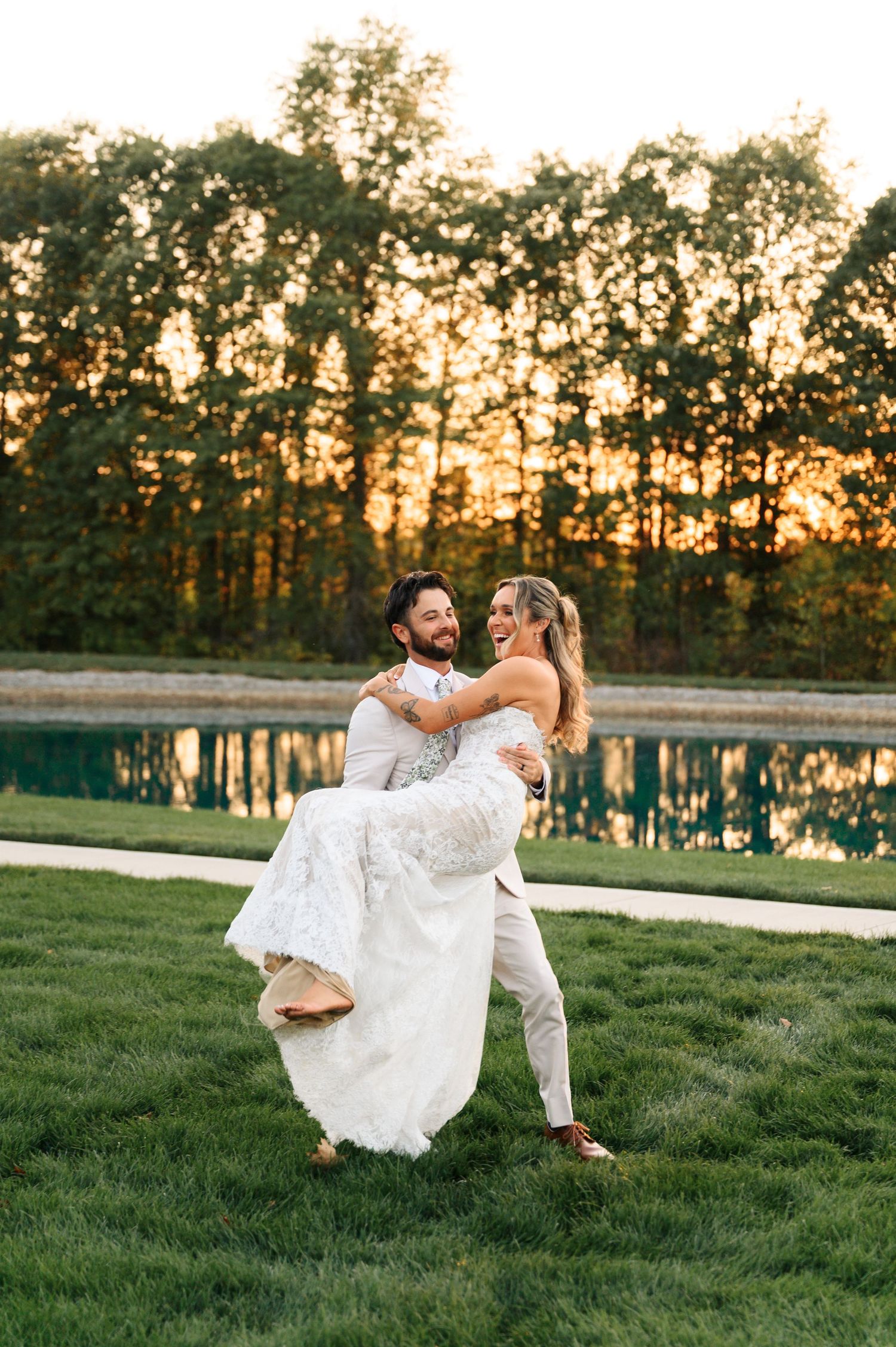 A couple shares an intimate moment on a pathway surrounded by vibrant red fall foliage and greenery.