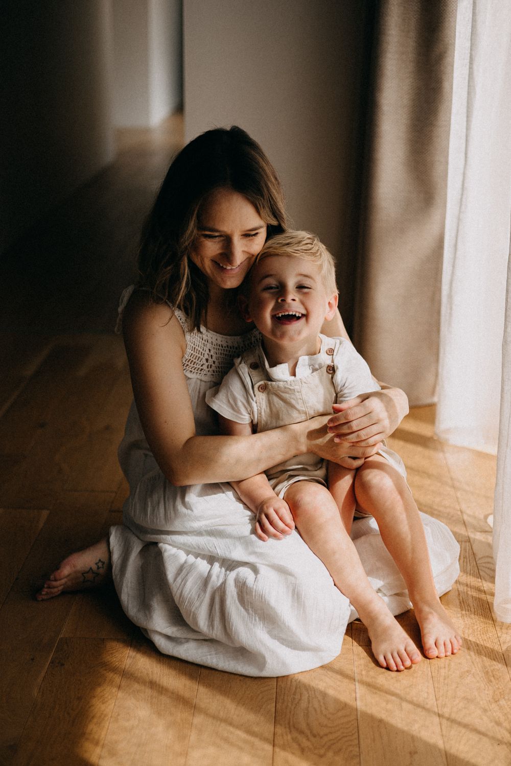 Candid moment of joyful interaction by window on wooden floor.
