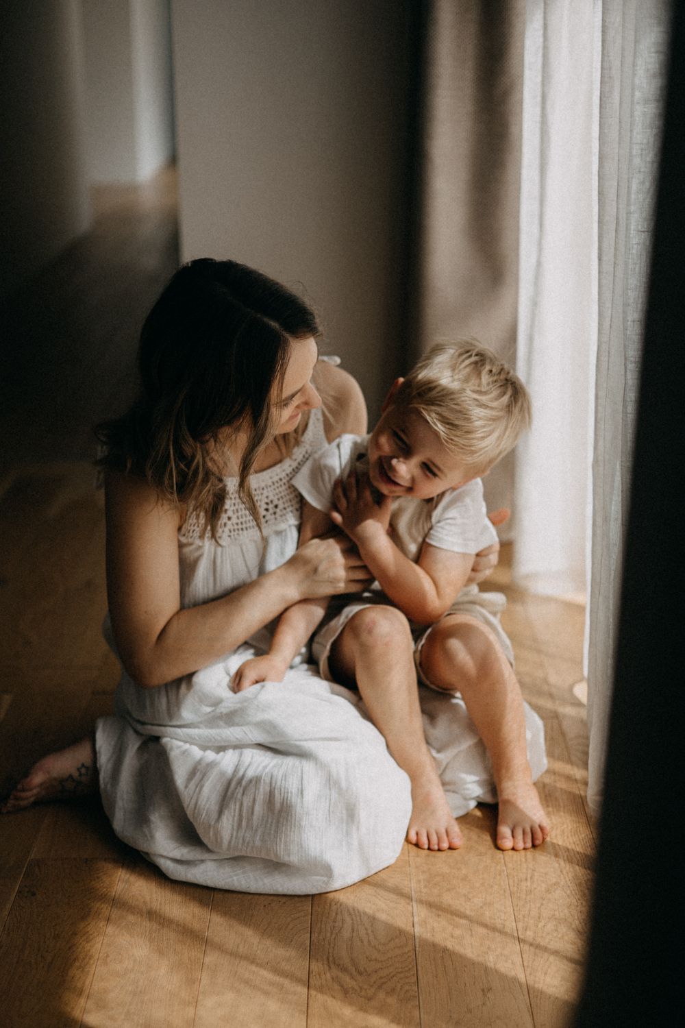 Sweet moment of laughter shared beside sunlit window.