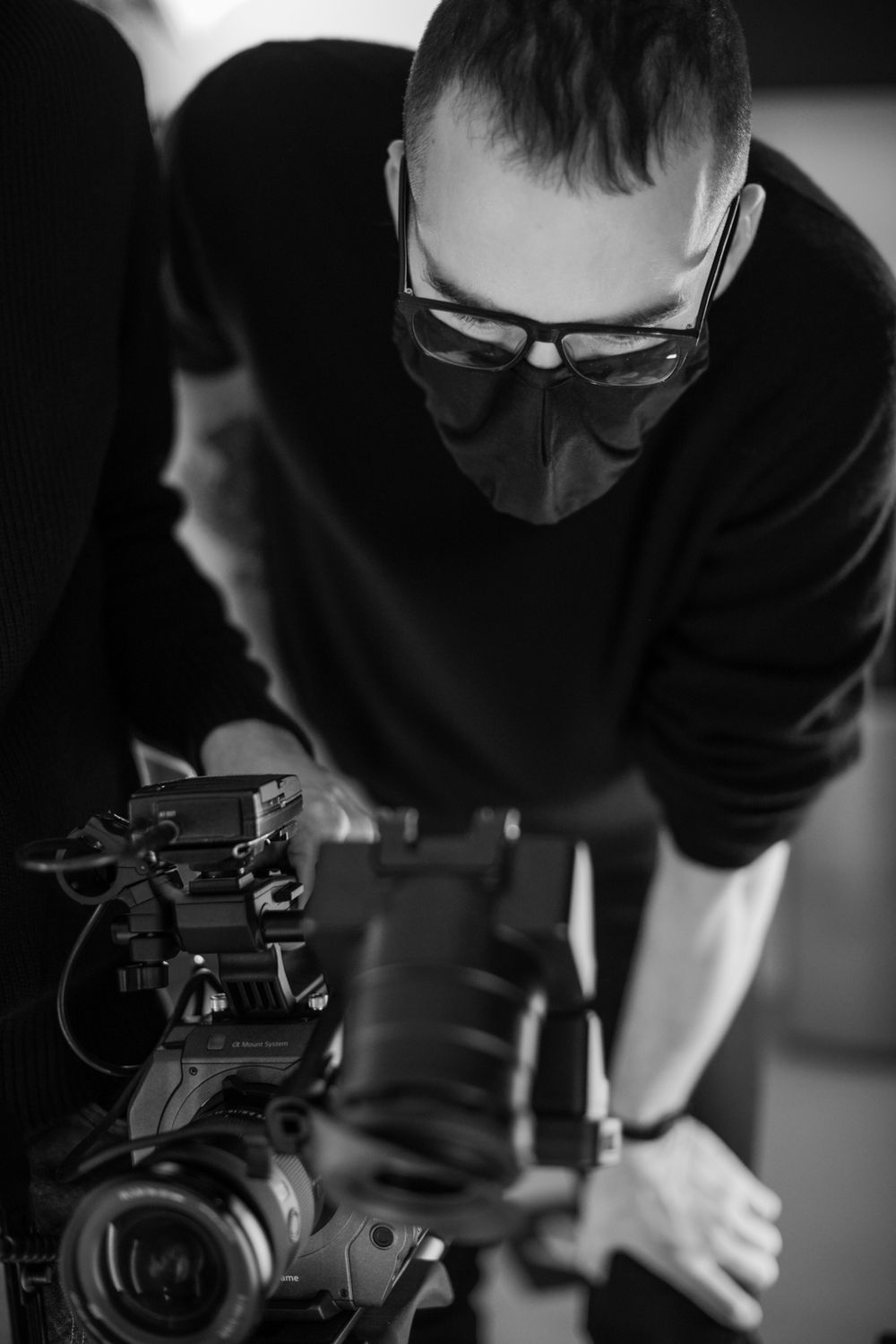 Camera operator adjusting professional video equipment during a shoot.