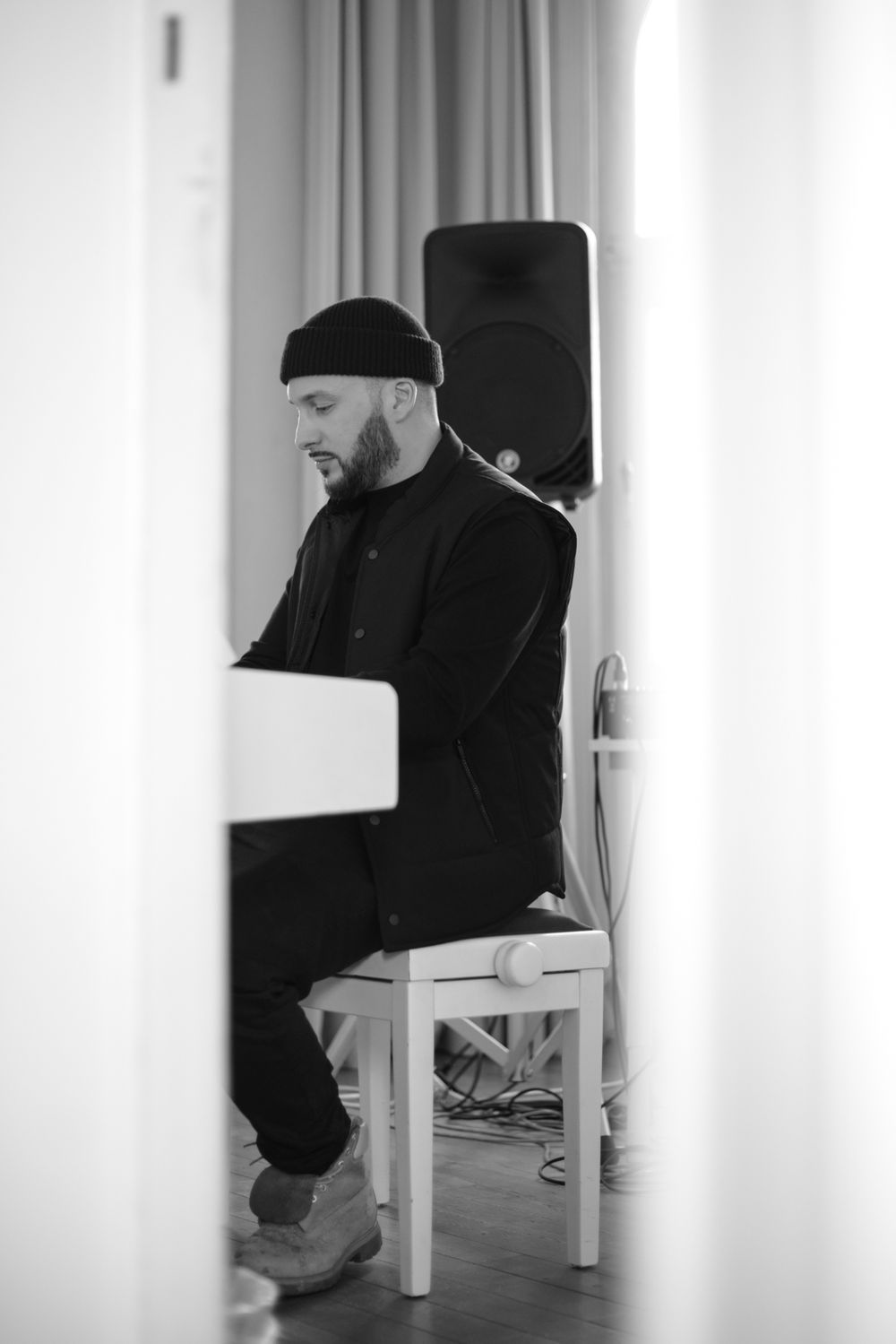 Artistic black and white minimalist photograph of a person sitting on a white chair against a light background.