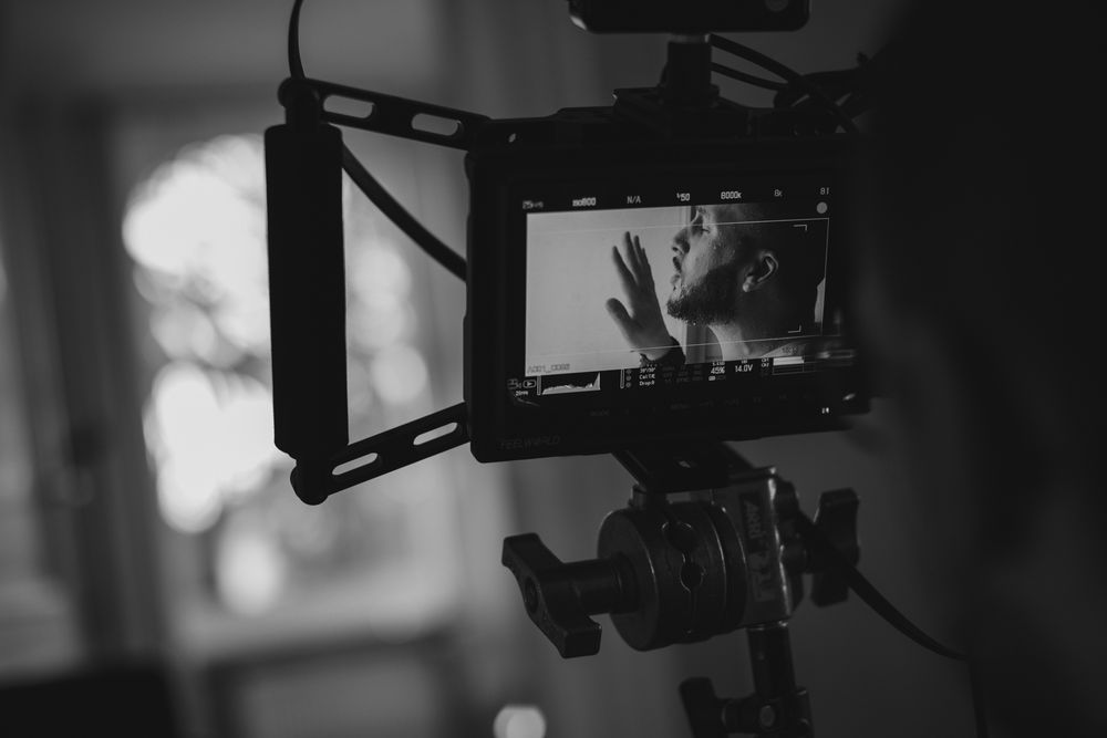 Professional camera equipment silhouetted against blurred background lighting.
