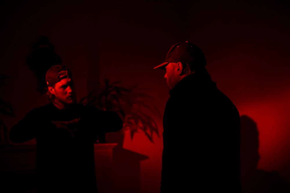 Silhouettes of figures performing against red-tinted atmospheric lighting.