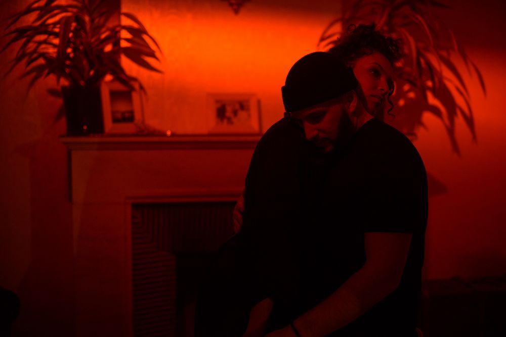 Room bathed in warm orange light with plant silhouettes and ambient mood.