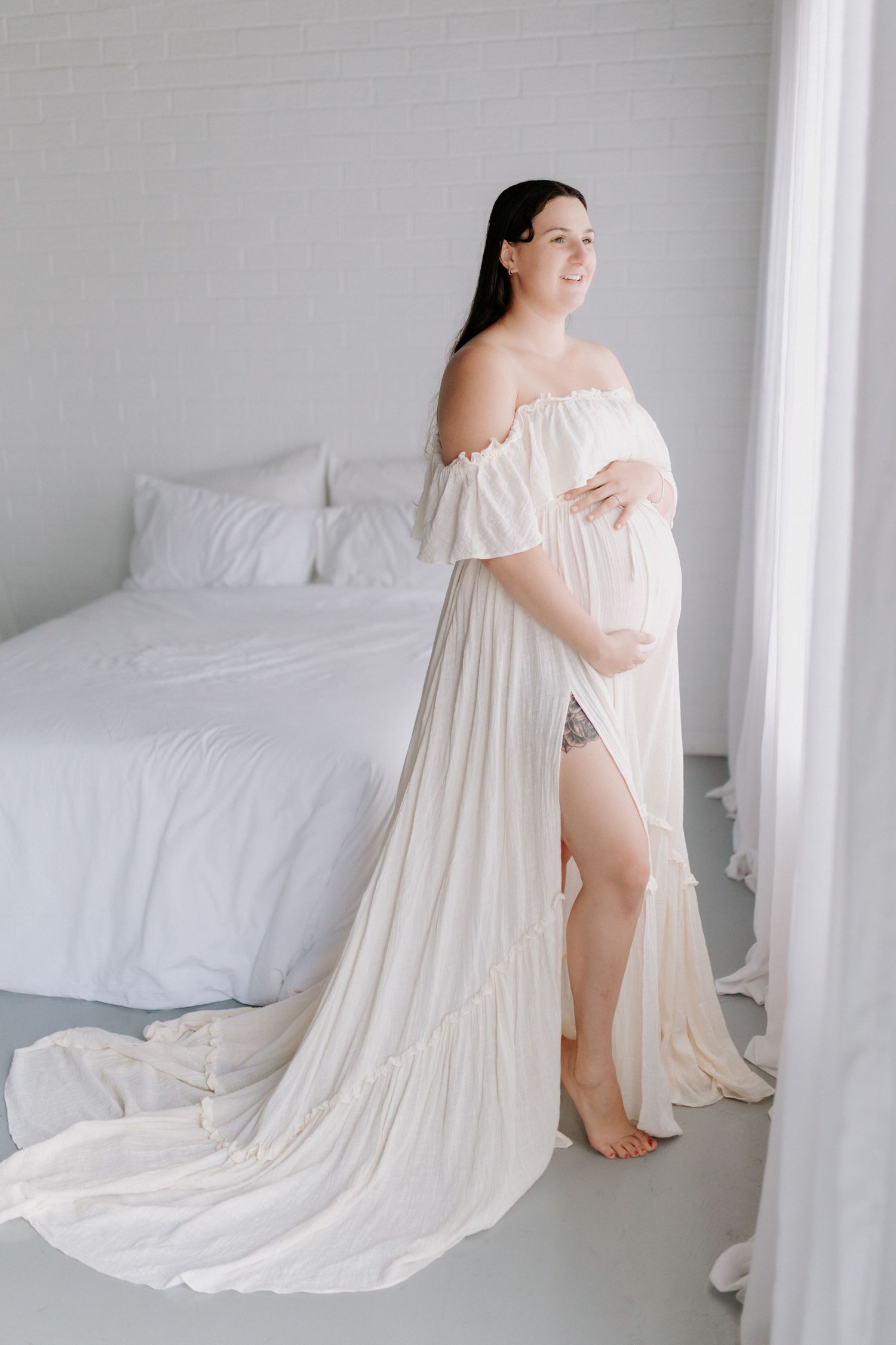Elegant off-shoulder cream wedding gown with flowing ruffles and dramatic chapel train displayed on mannequin.