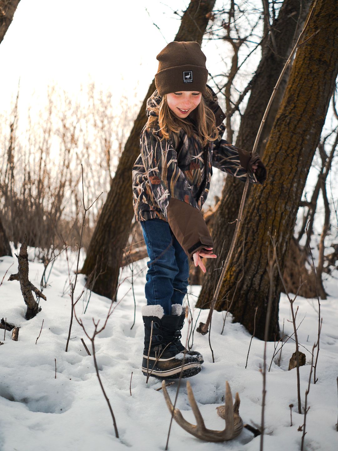 Winter hunting scene with outdoor enthusiast examining antlers in snowy forest.