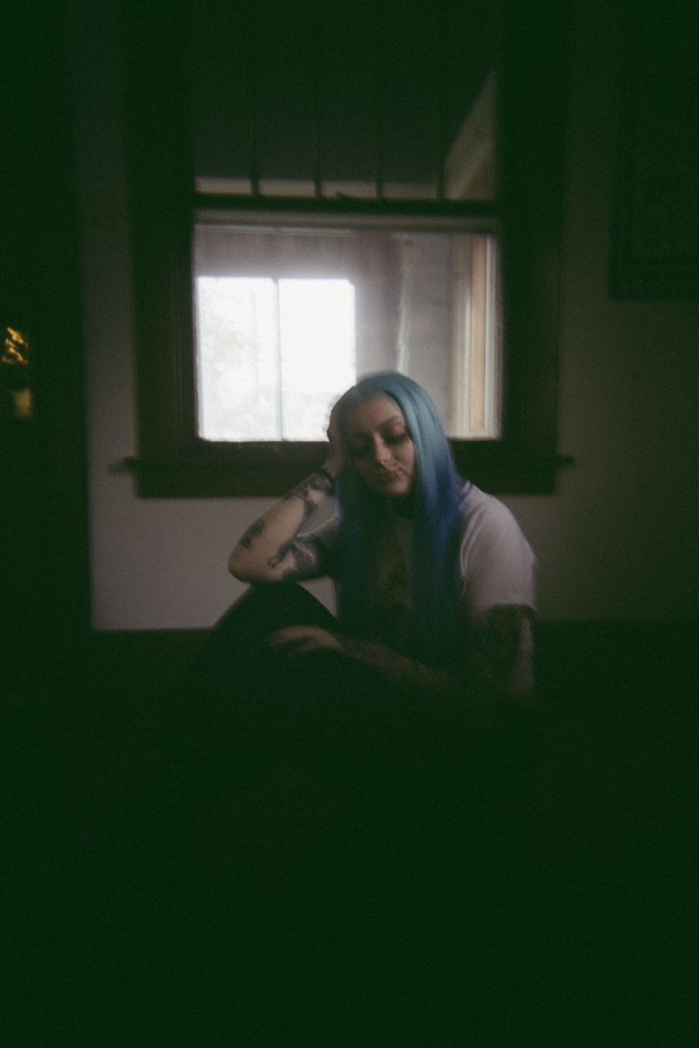 A dark atmospheric photo captures a figure resting in a shadowy interior space.