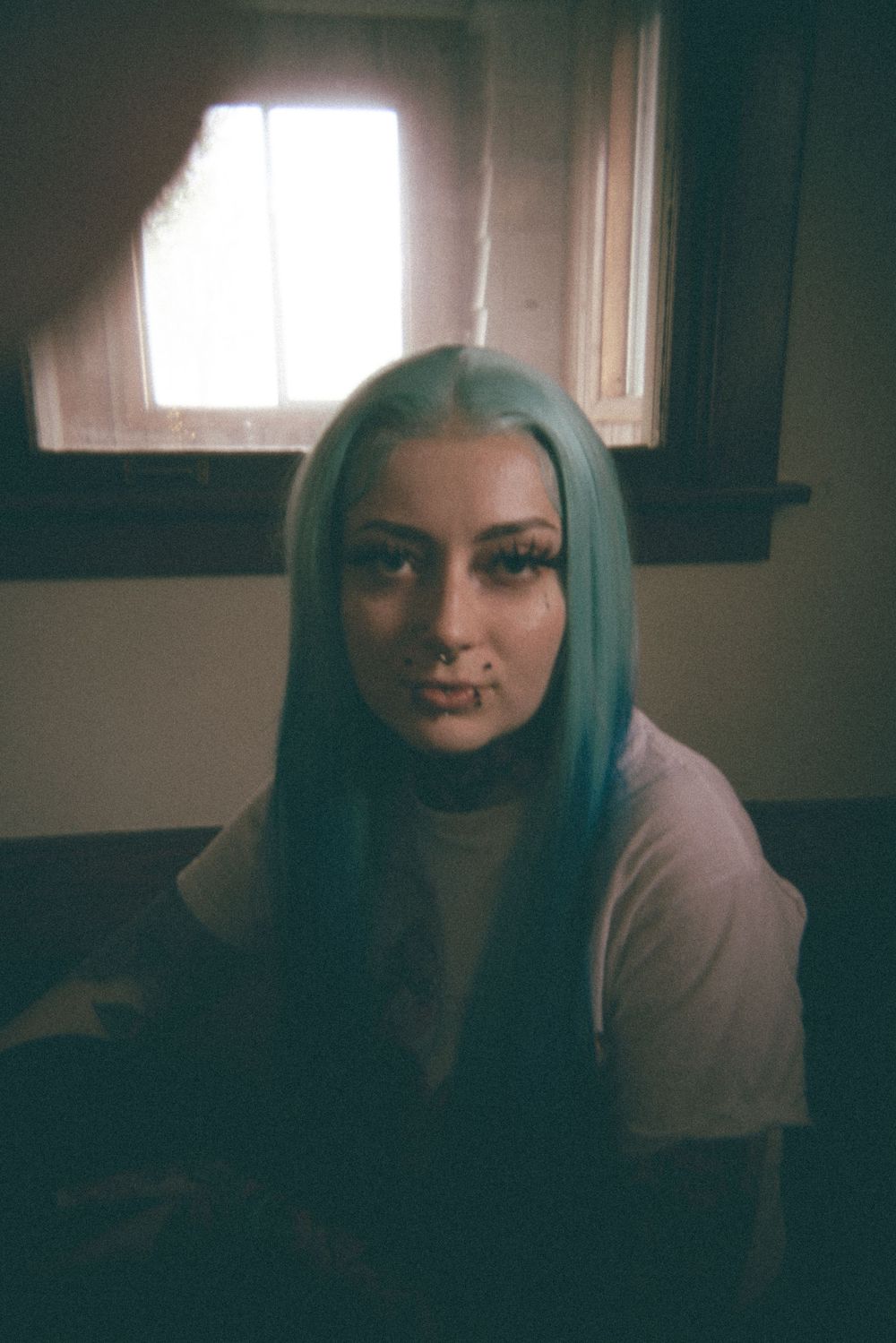 Series of expressive shots in dim lighting showing bright blue hair and dramatic shadows.