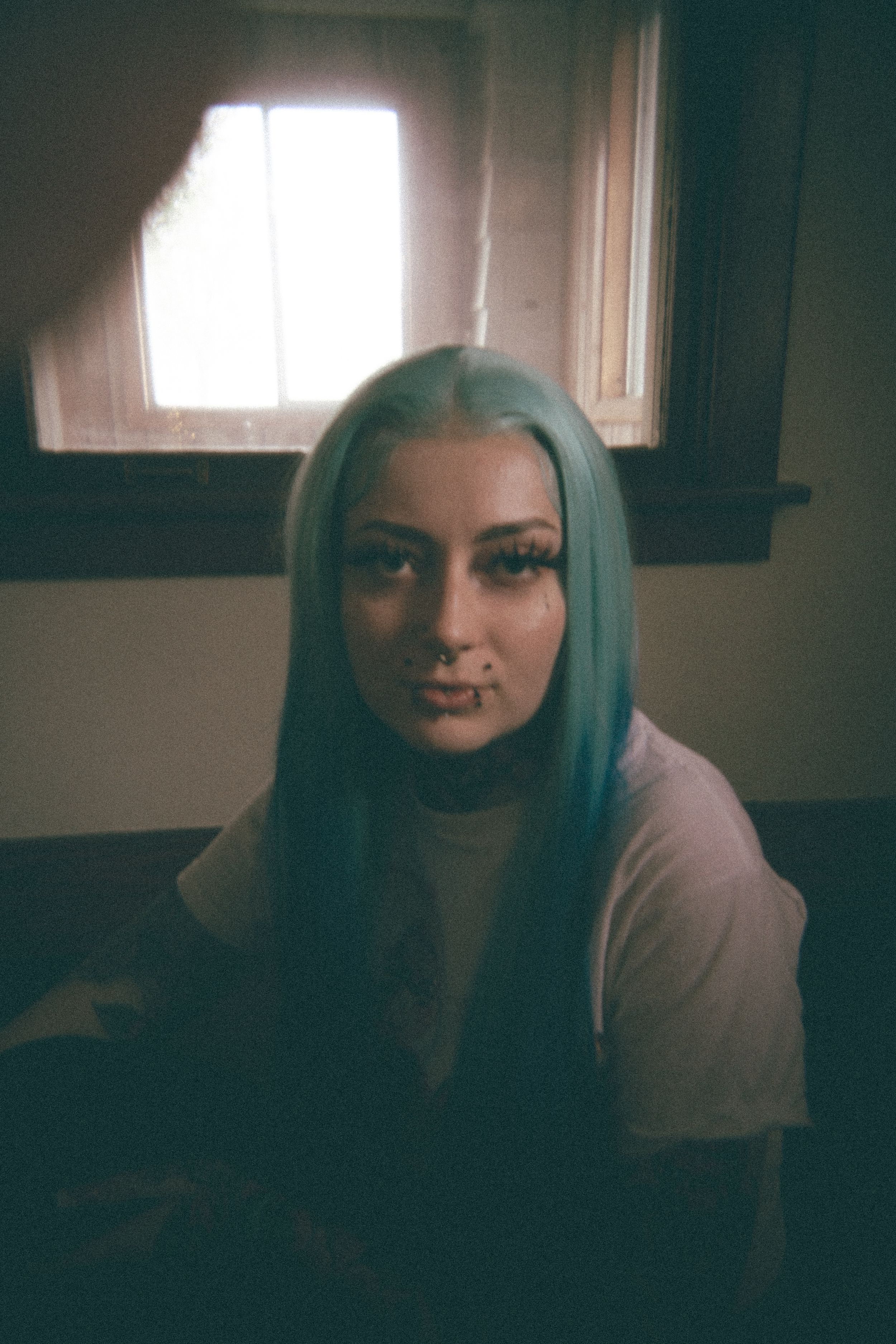 Series of expressive shots in dim lighting showing bright blue hair and dramatic shadows.