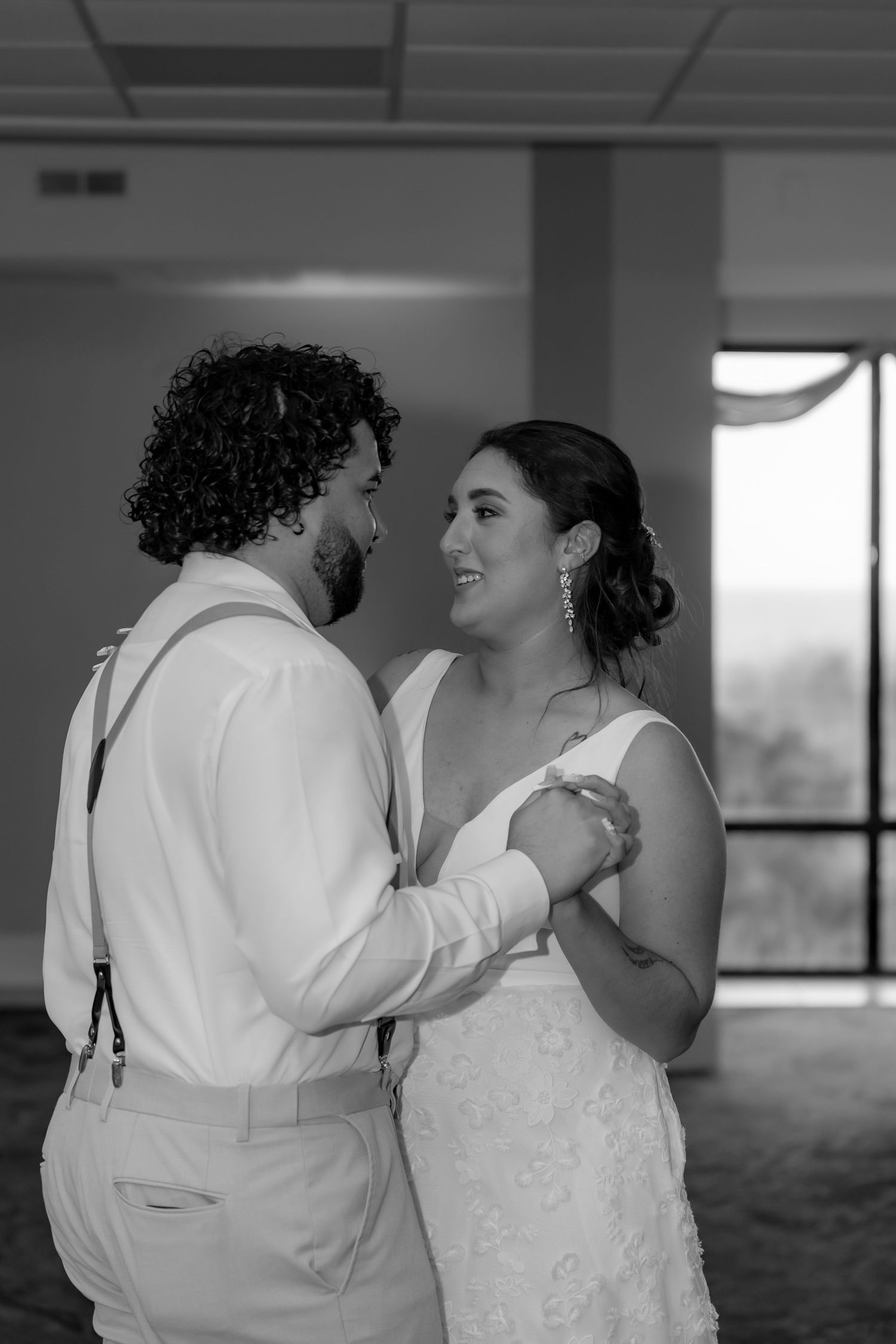 A loving couple shares a tender moment during their first dance at their wedding reception, captured in black and white.