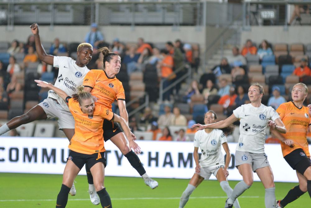 Players battle for possession during an aerial challenge in a soccer match.