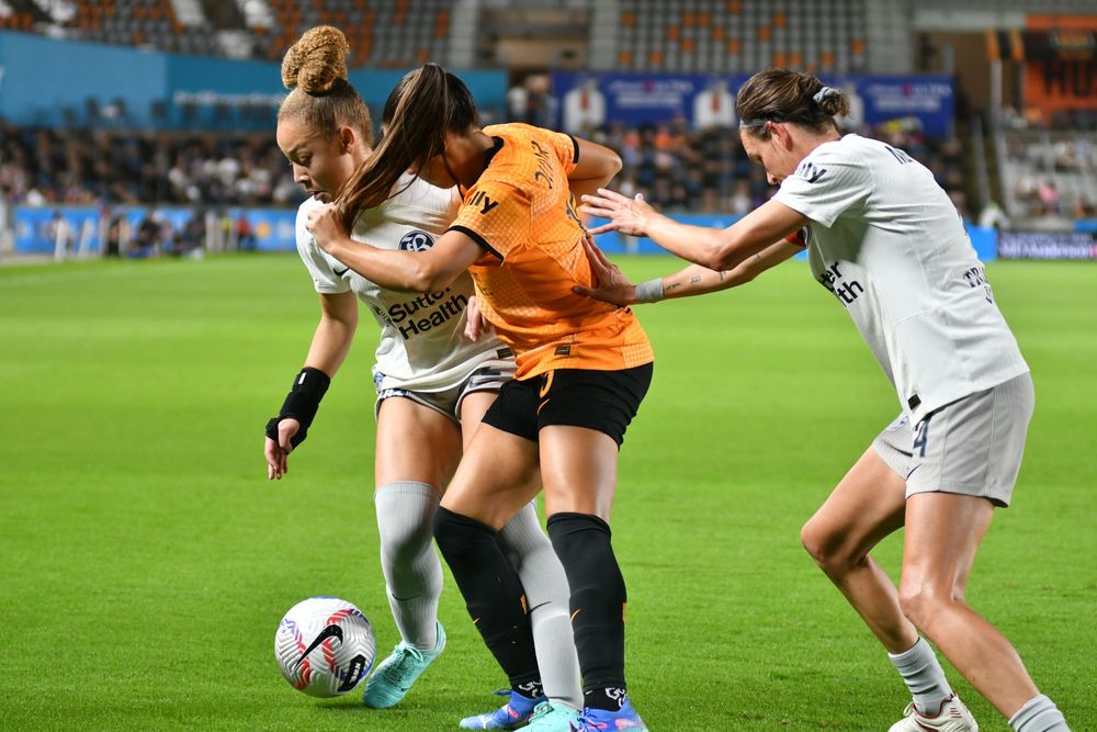 Soccer players engage in intense physical battle for ball possession during match.