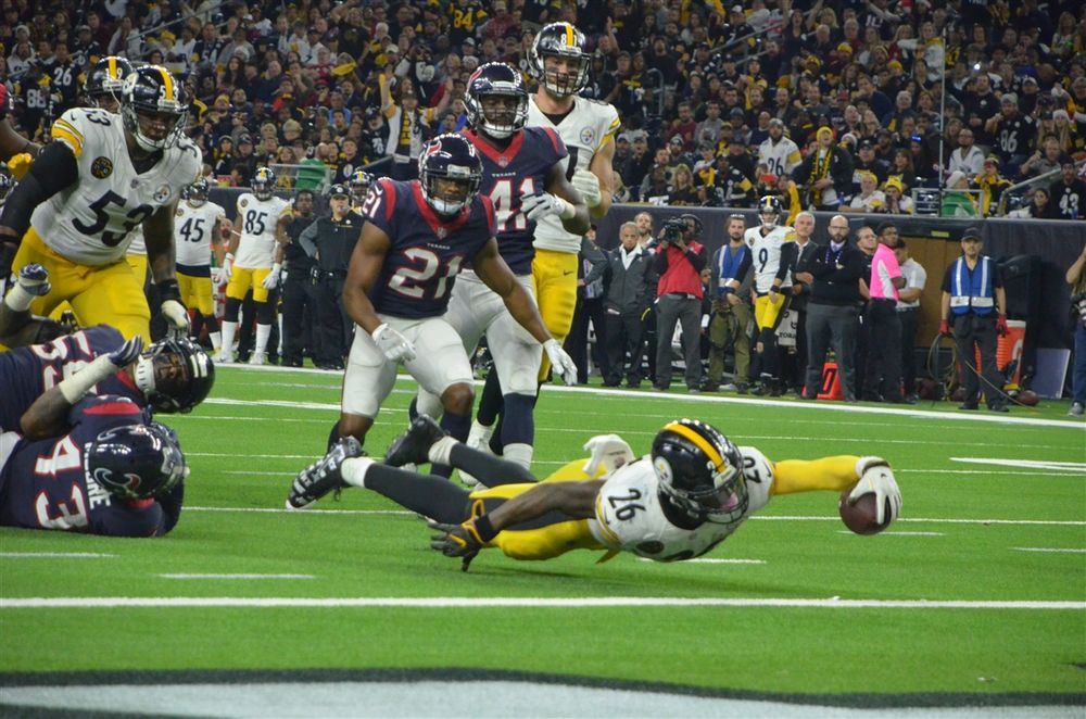 Multiple players dive for a loose football during an intense NFL game play.