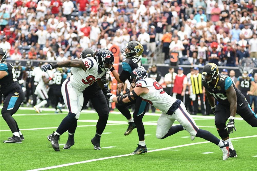 NFL players from opposing teams battle at line of scrimmage during intense game action.