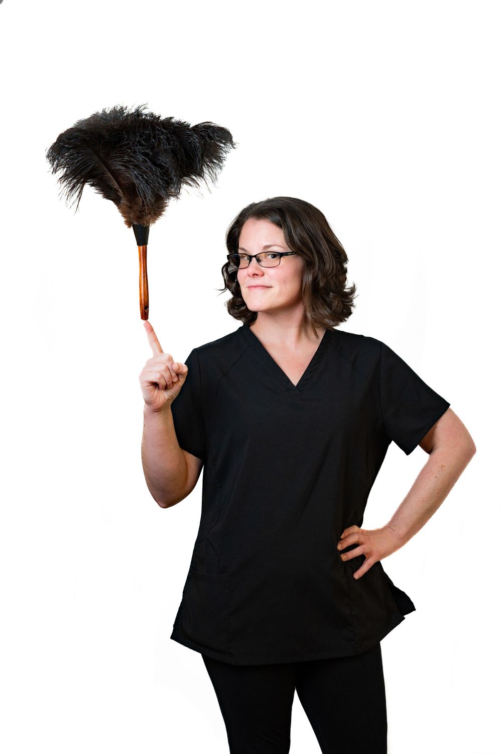 Professional in black scrubs holds up a feather duster with a confident pose against white background.