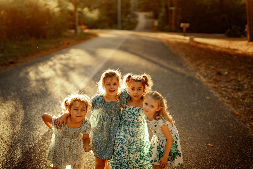 Children playing together on a sunlit country road during golden hour with warm autumn lighting.