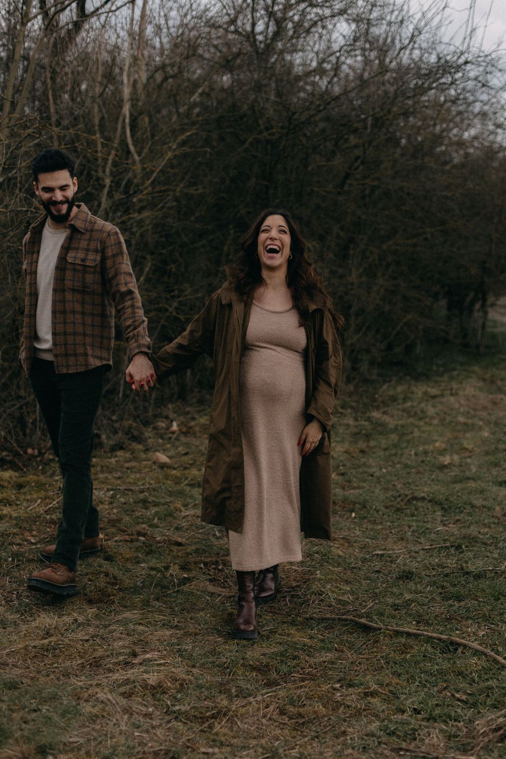 Joyful moment shared while walking outdoors during a winter maternity session.
