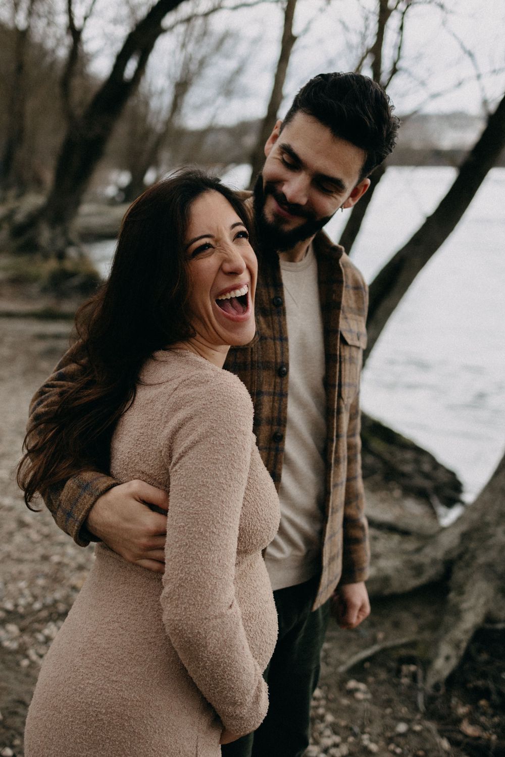 Joyful couple sharing a laugh during their outdoor maternity photo session.