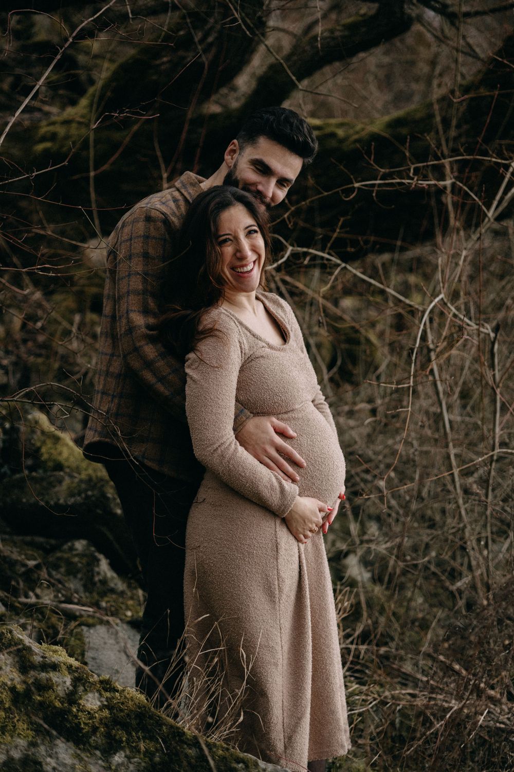 Expecting parents share a happy moment during their outdoor winter photoshoot.