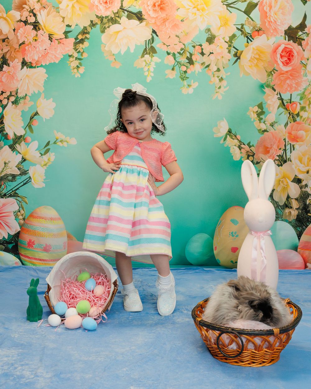 Easter portrait setting with pastel flowers, decorative eggs, and bunny decor against turquoise backdrop.