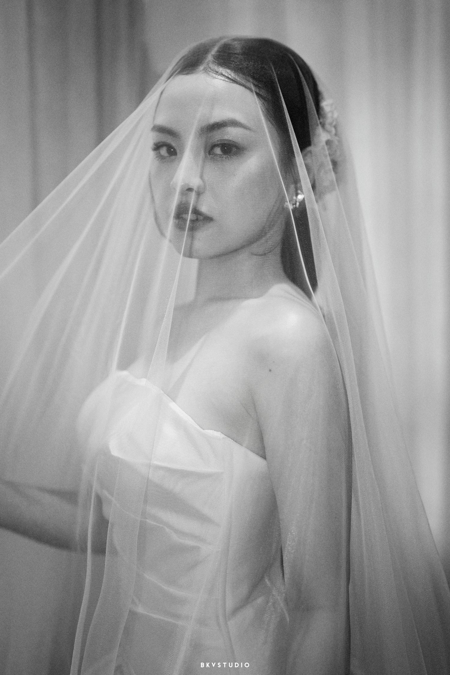 A stunning black and white bridal portrait featuring a long flowing veil and strapless wedding dress.
