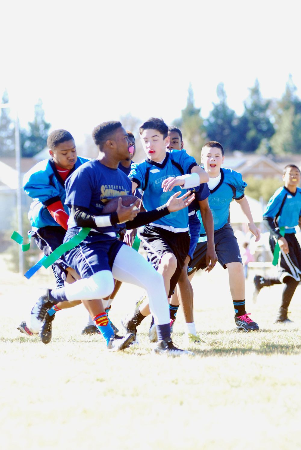 Game action of youth flag football on an outdoor field.