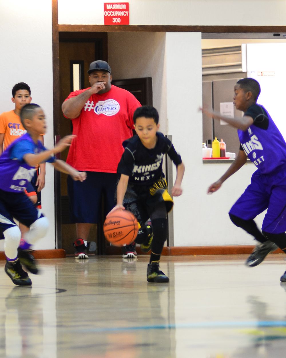 A youth basketball game showing a player dribbling down the court.