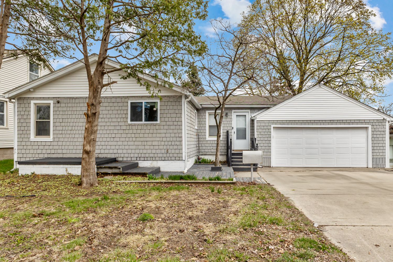 Ranch-style home with cedar shake siding, attached two-car garage, and concrete driveway.