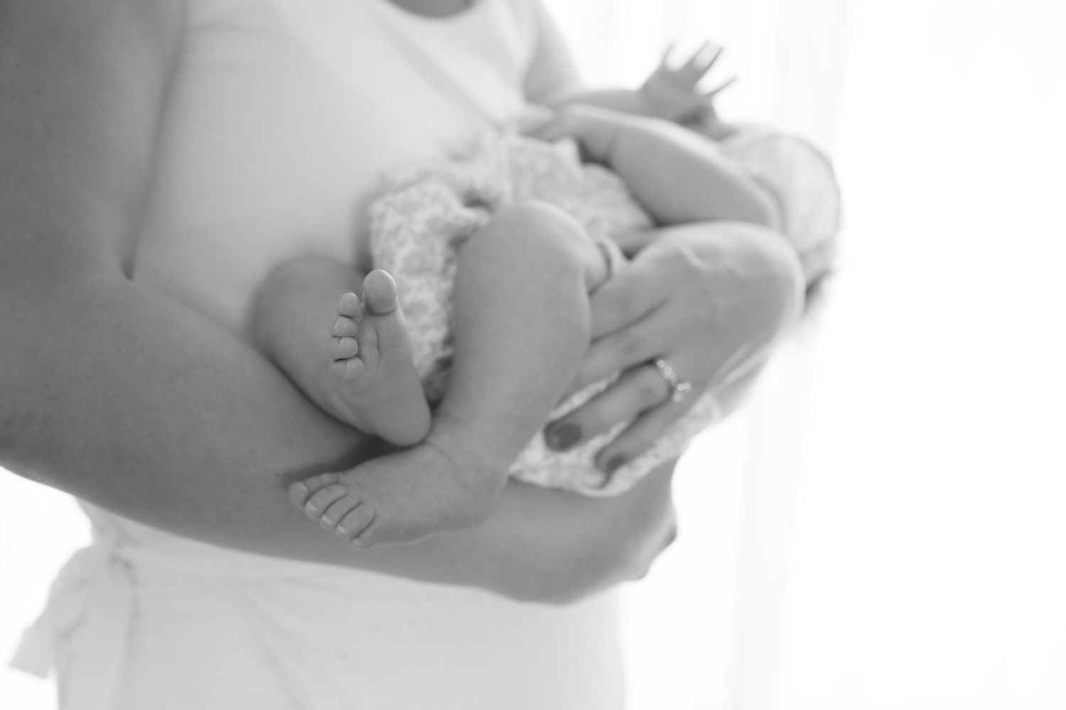 closeup of newborn baby's feet while mom is holding baby during in home lifestyle newborn session in somerset, wi