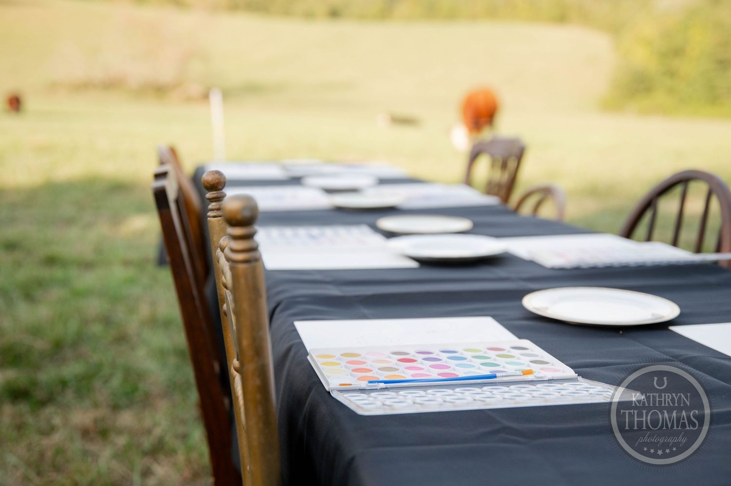 Black table with watercolor paint set, brushes, and a bear outline drawing ready for a kids art activity.