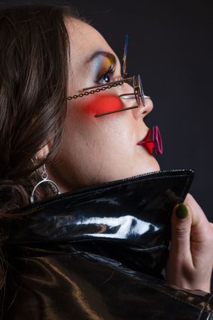 Profile portrait of a woman wearing avant-garde glasses with bold red and blue makeup.