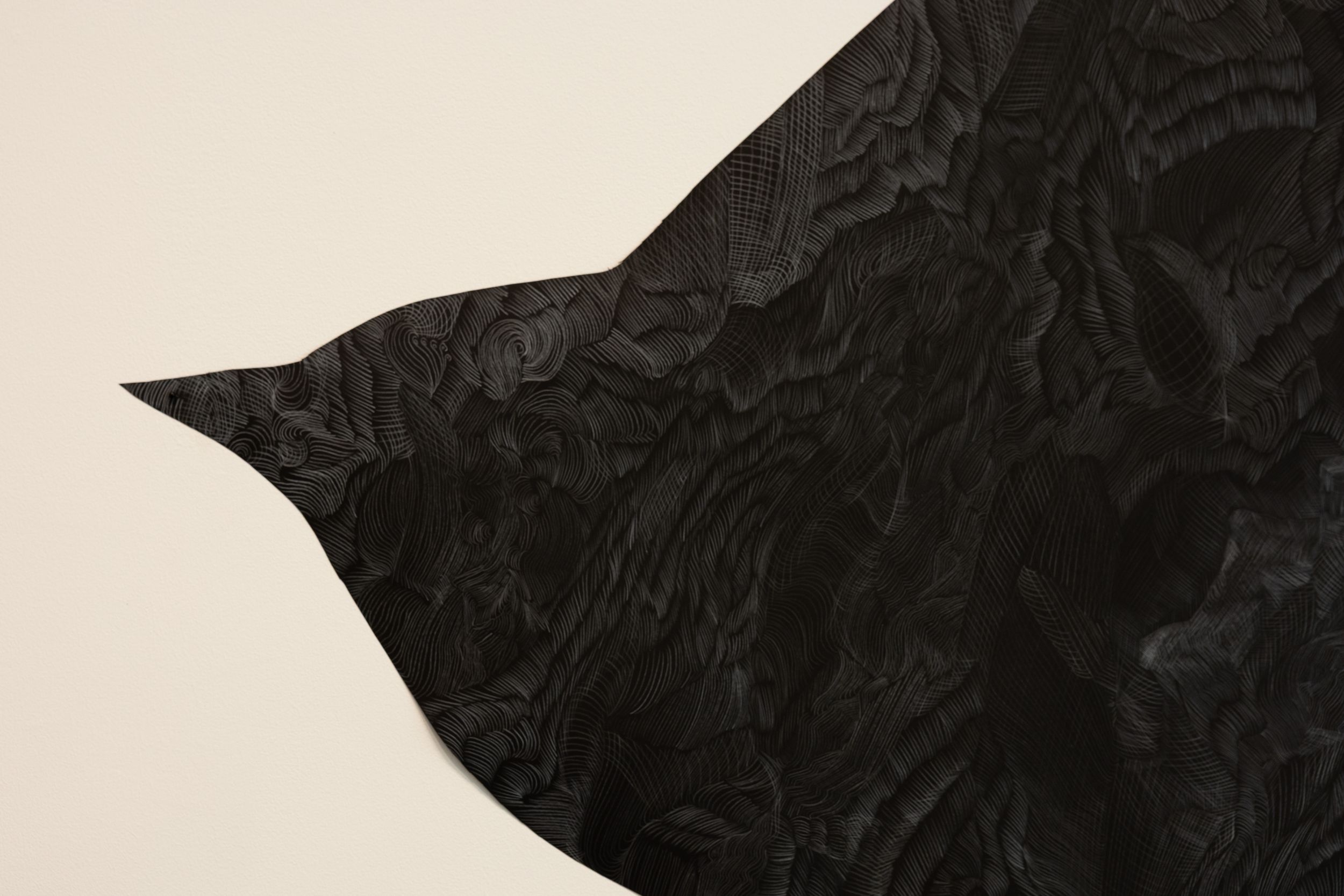 Detail of a black sculptural bird wing artwork with textured surface against cream background.