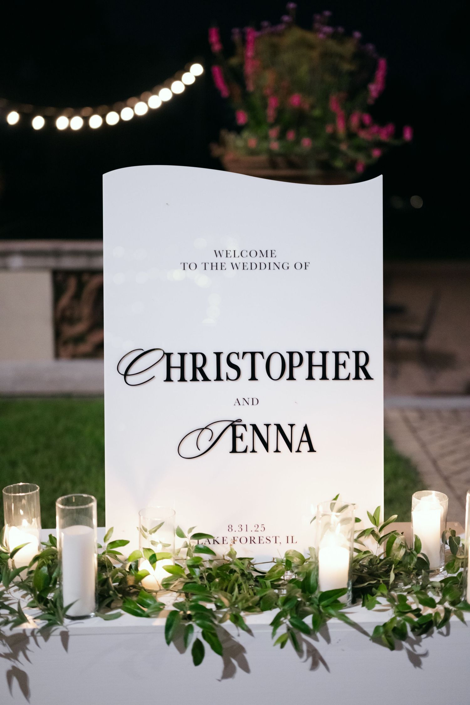 Elegant wedding reception table with champagne flutes, floral centerpiece, cake slice, cocktails, and place cards on white linen.