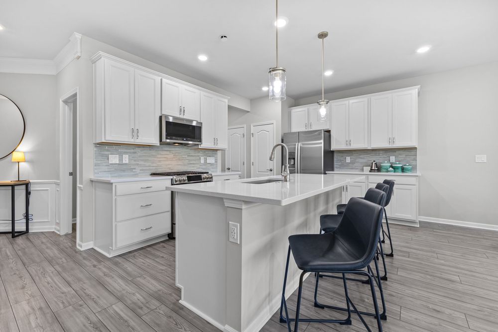 Modern kitchen with white quartz island and stainless appliances in Walled Lake townhome