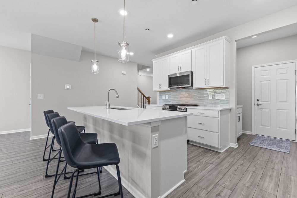 Modern kitchen with white quartz island and stainless appliances in Walled Lake townhome
