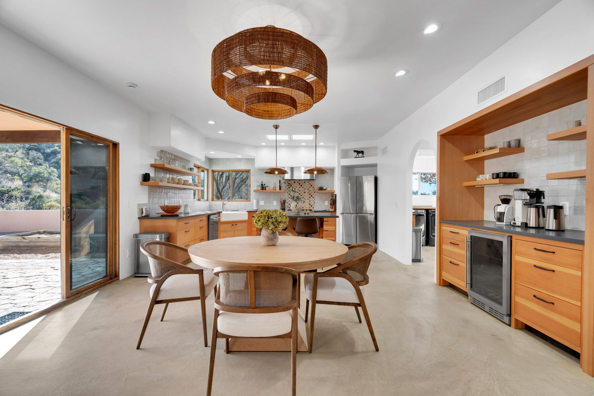 Modern kitchen and dining area with wooden cabinetry and sleek white walls showcasing open concept design.