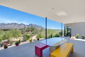 Colorful outdoor patio seating area with benches overlooking desert mountain landscape and blue skies.