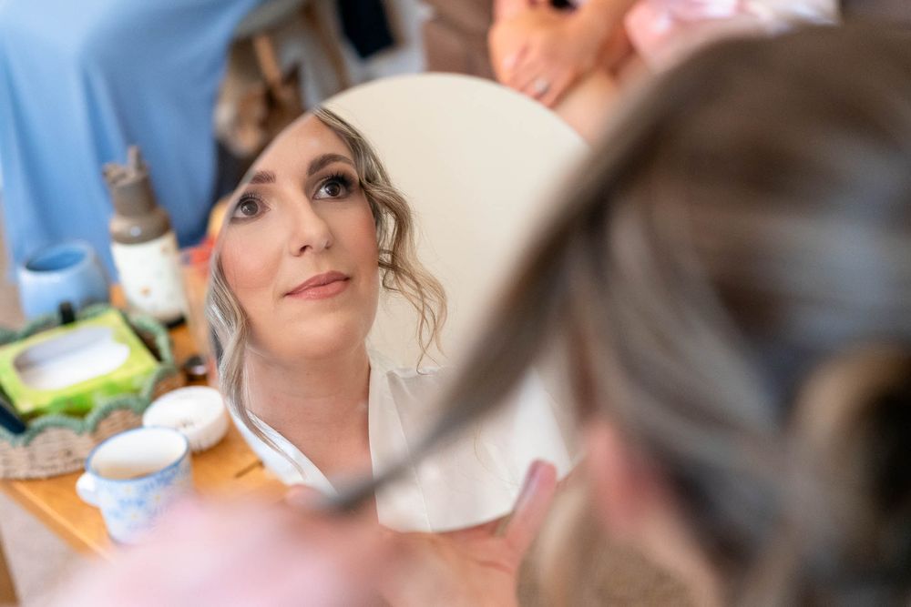 Brides face in small mirror for a Corn Barn Devon Wedding