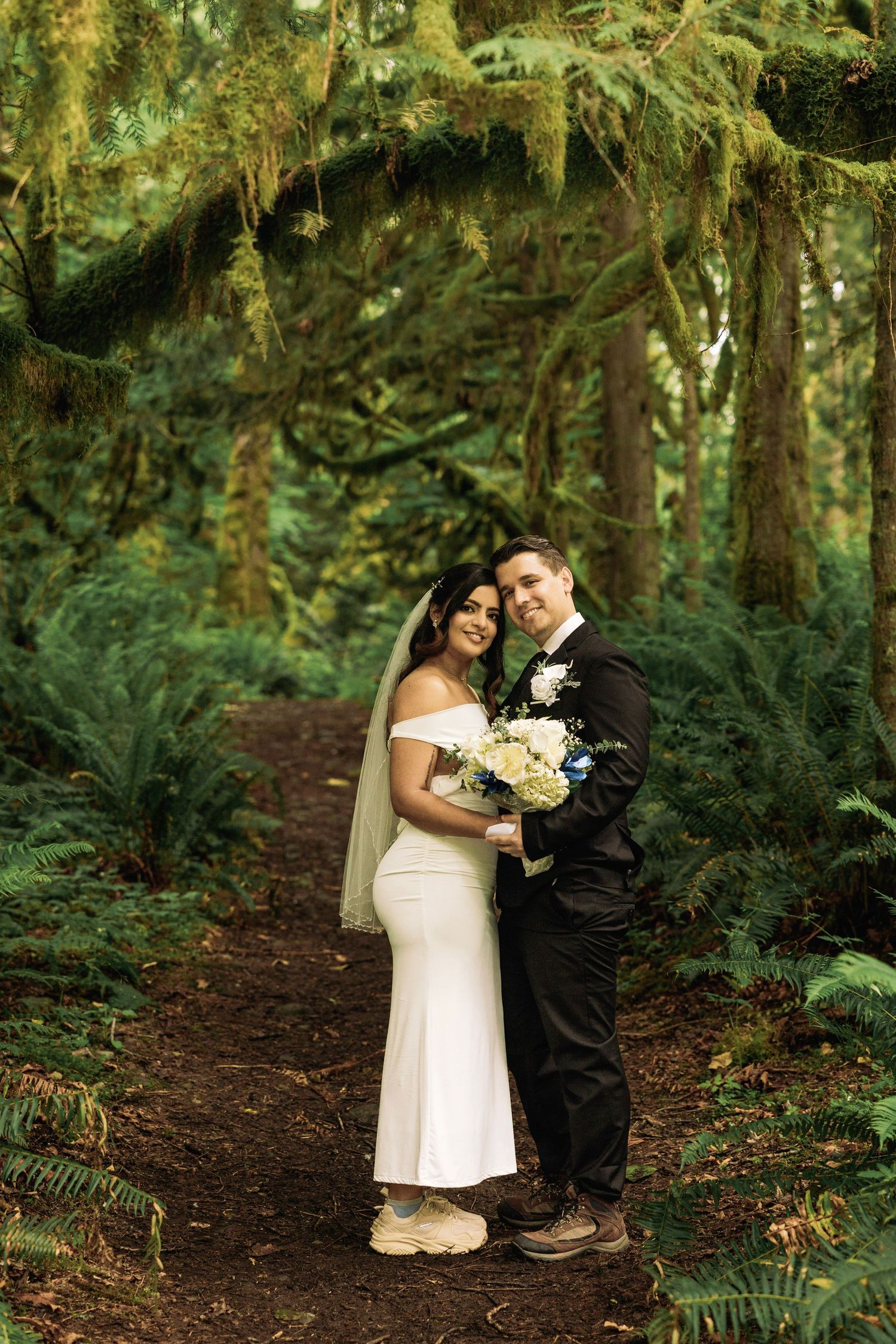 A bride and groom share a romantic moment near a waterfall, with the bride in white and groom in a black suit.