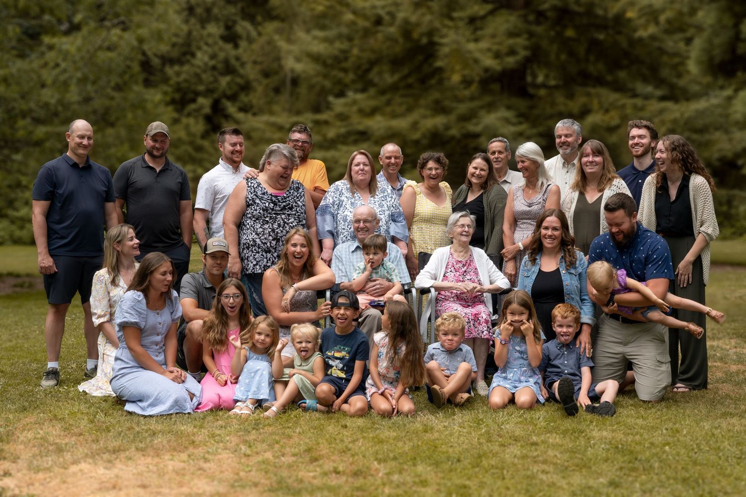 Large extended family gathering with multiple generations posed together outdoors.