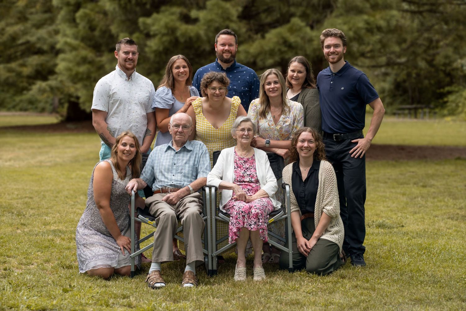 Extended family members gather for a group portrait in a park setting.