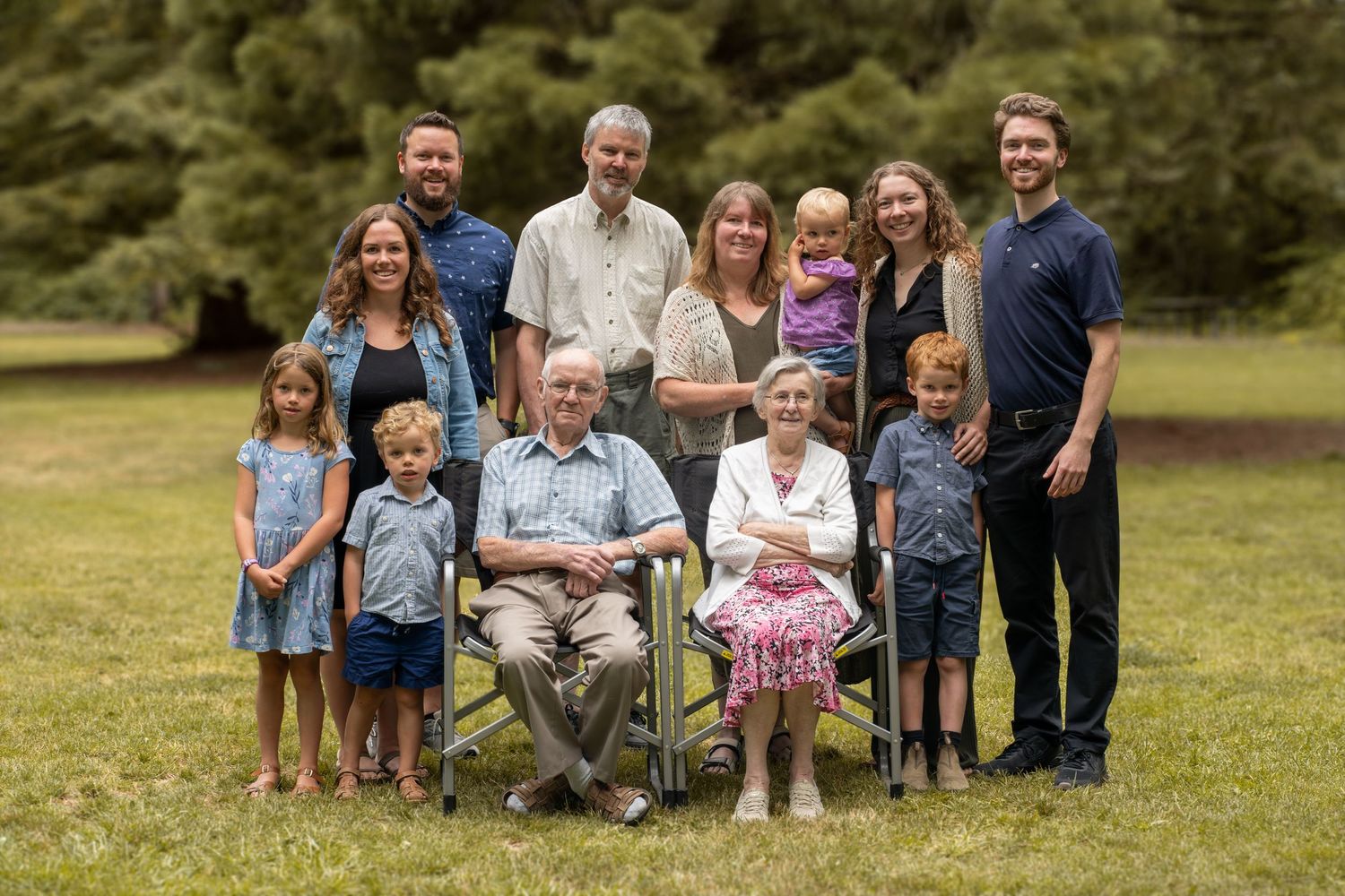 Multi-generational family photo with grandparents seated in center and children standing around them.