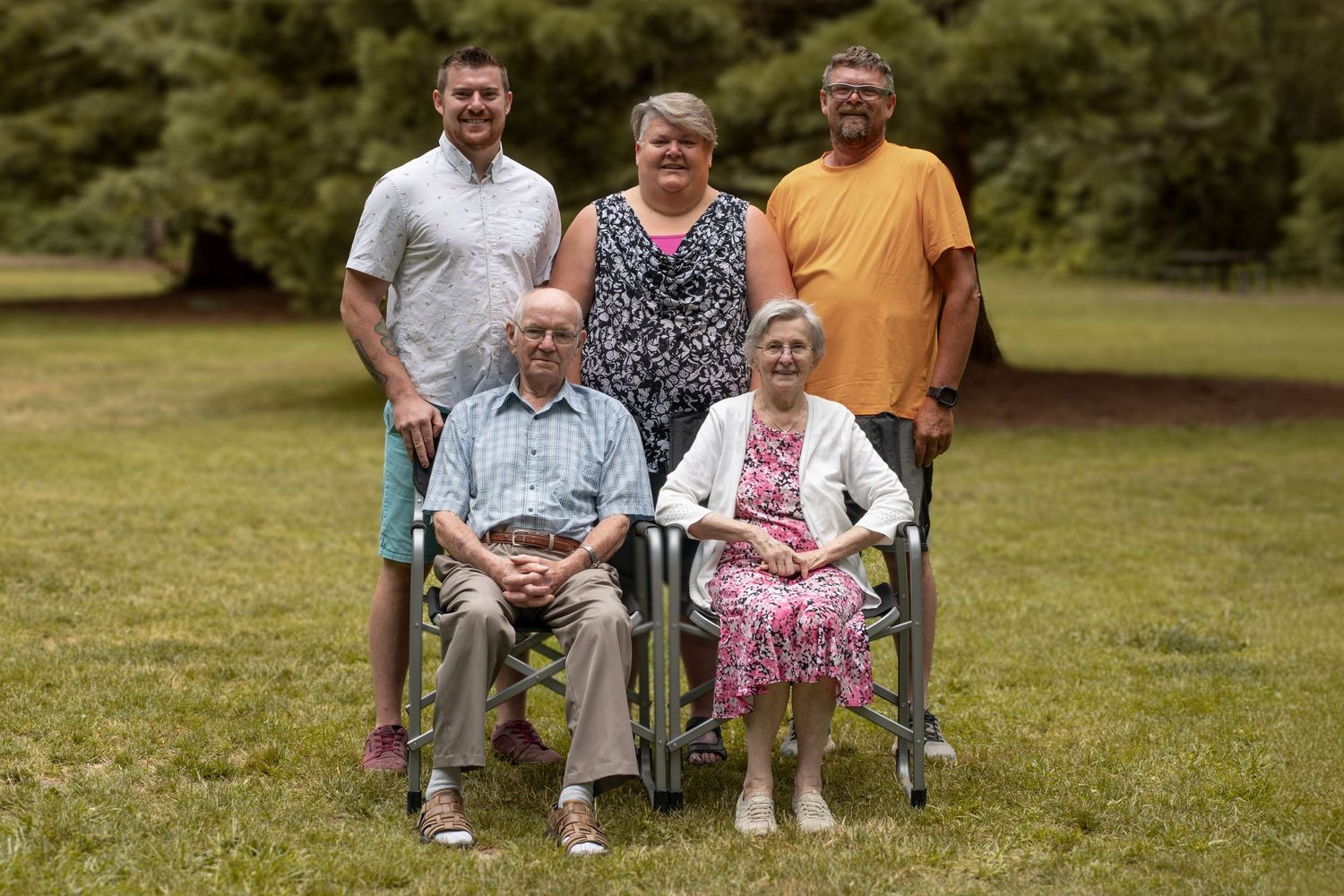 A multi-generational family group poses together outdoors with seniors seated in front.