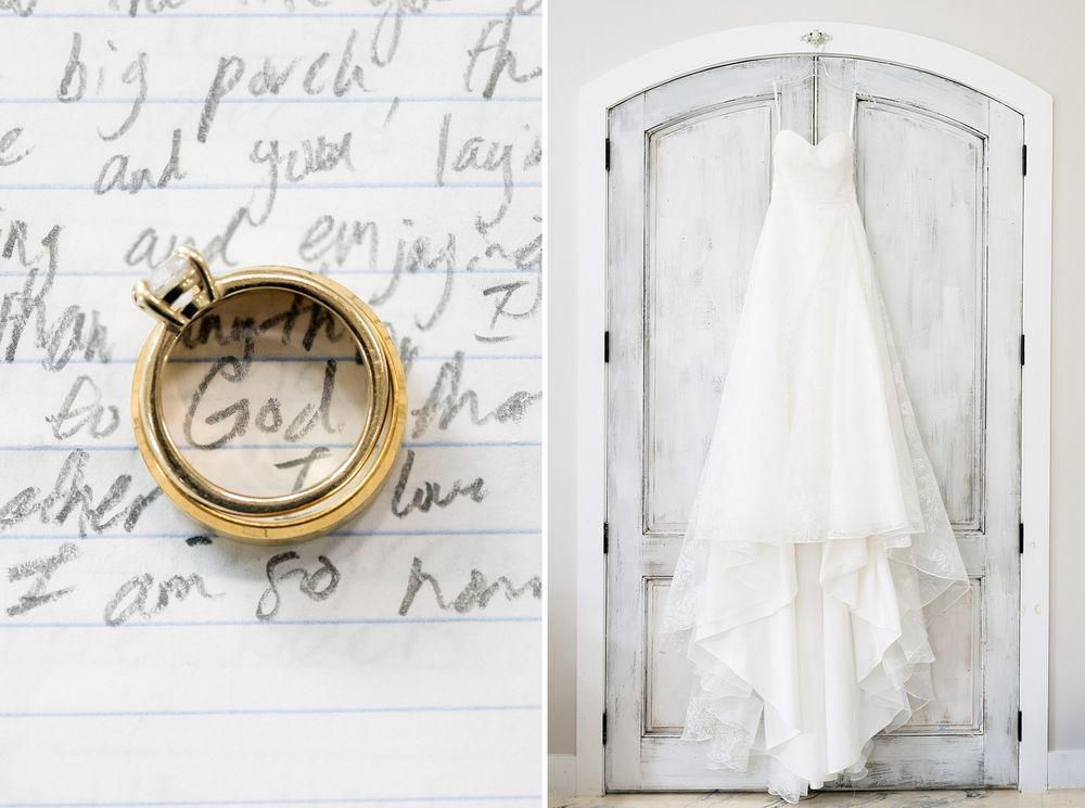 Gold wedding rings on handwritten letter beside a white wedding gown hanging on a rustic door.