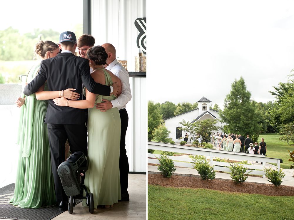 Wedding party sharing an emotional group hug outdoors near a white venue surrounded by green landscaping.