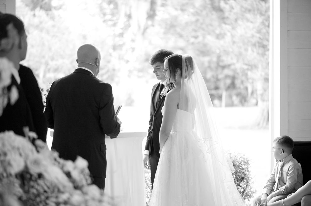 Bride and groom exchange vows during an elegant indoor wedding ceremony in black and white photo.