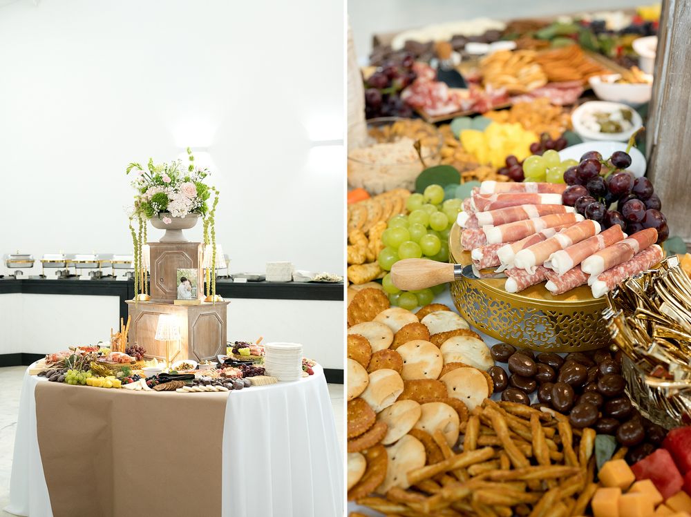 Elegant wedding charcuterie display with tiered floral centerpiece, assorted crackers, cured meats, fresh grapes, and gourmet cheeses.