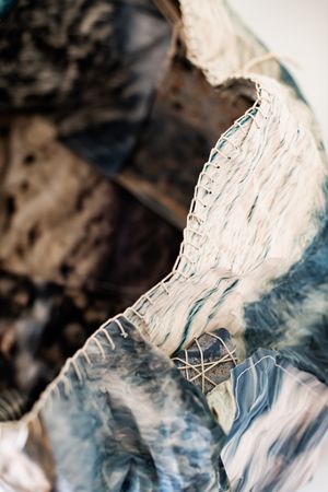 Close-up of textured blue and white tie-dye fabric sculpture with intricate stitching and woven details.