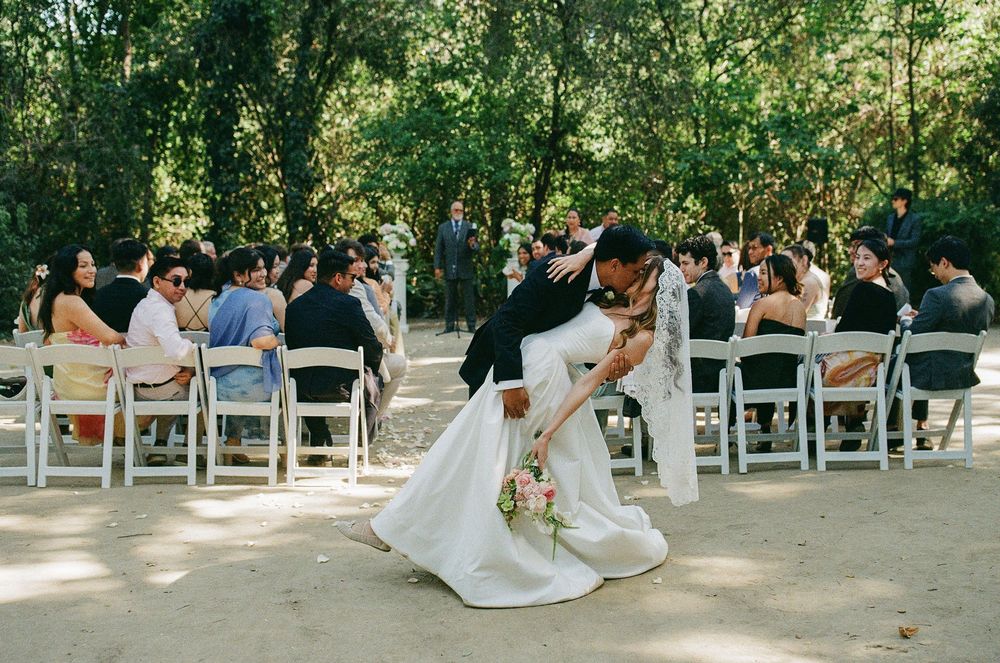 A garden wedding setting in California from bicoastal wedding photographer Holly Castillo. A groom dips a bride in a dramatic kiss.